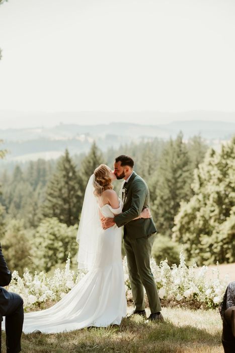 bride and groom kissing at their outdoor summer wedding ceremony in front of a ground floral meadow in portland oregon