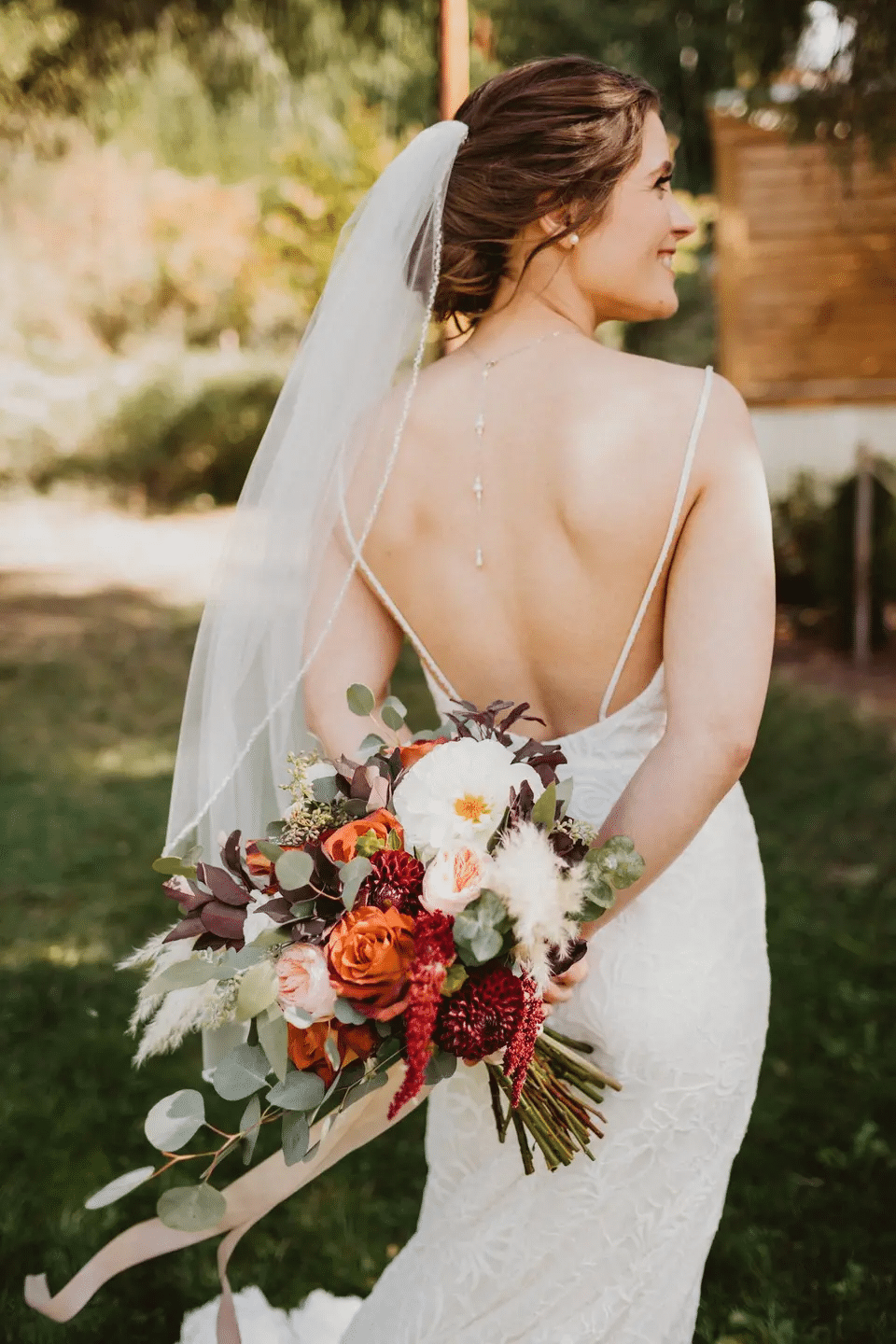 bride holding her bridal bouquet behind her back at an outdoor autumn wedding at Vernonia Springs wedding venue in Oregon