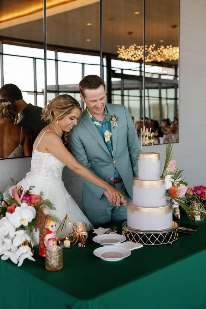 bride and groom cake cutting at a modern tropical wedding at ironlight, cake flowers designed by Flowers by Alana